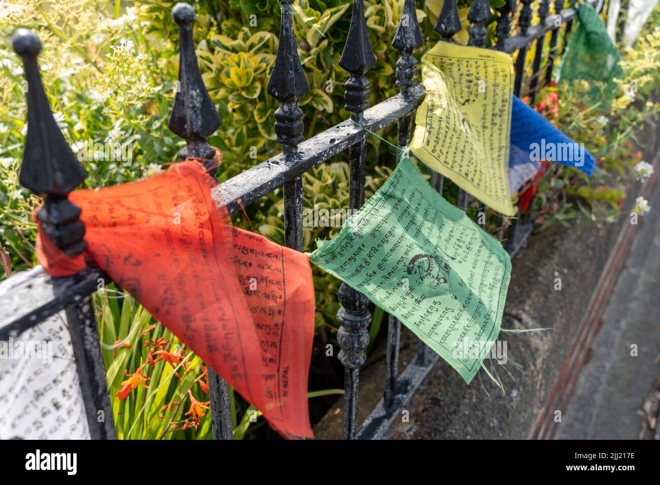 Bandiere di preghiera tibetane dai colori vivaci lungo la ringhiera di un giardino a Cullercoats, Regno Unito Foto Stock