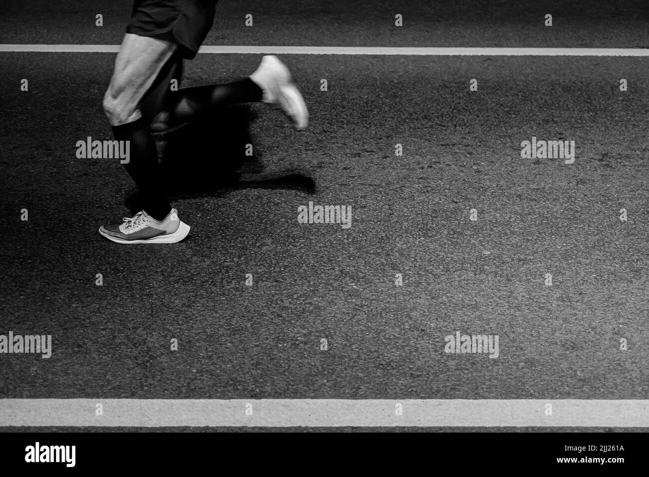 l'atleta del corridore delle gambe corre sull'asfalto di notte Foto Stock