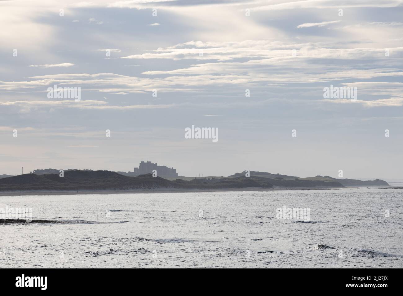 La silhouette del Castello di Bambburgh alla luce della sera dalle Seahouses, Northumberland, Inghilterra Foto Stock