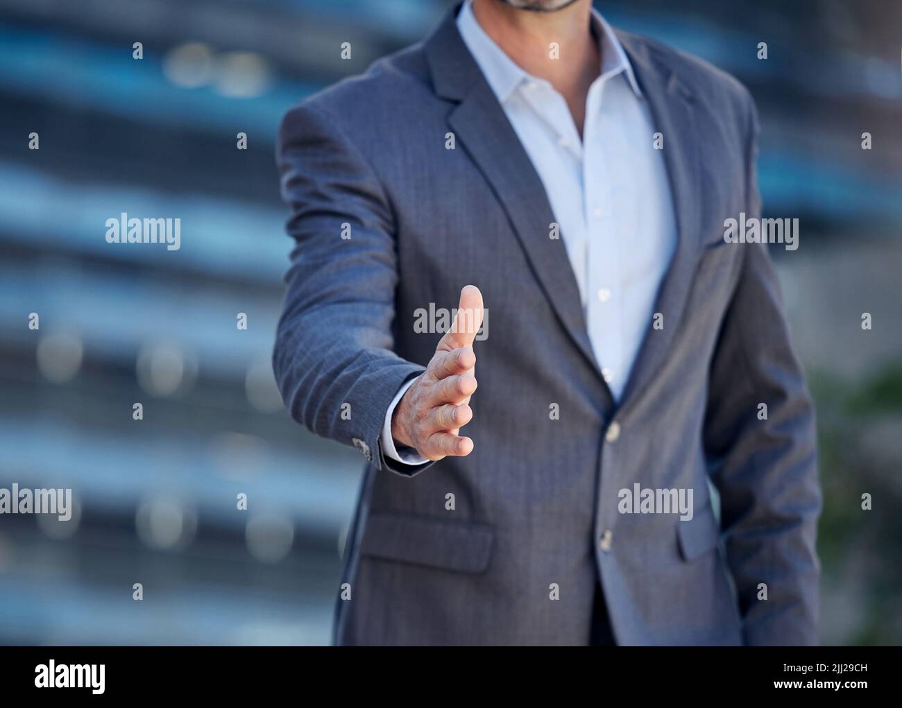 Lascia il lavoro, un uomo d'affari irriconoscibile che allunga la mano per una stretta di mano contro uno sfondo urbano. Foto Stock
