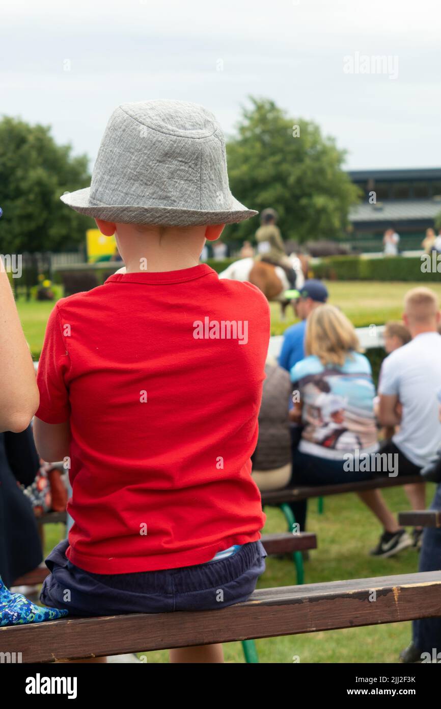 Torna di bambino in rosso teeshirt e cappello guardando un cavallo che mostra classe al Great Yorkshire Show Harrogate Inghilterra Foto Stock