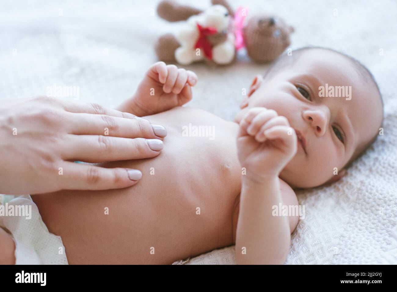 le mani della madre picchiano delicatamente il neonato Foto Stock