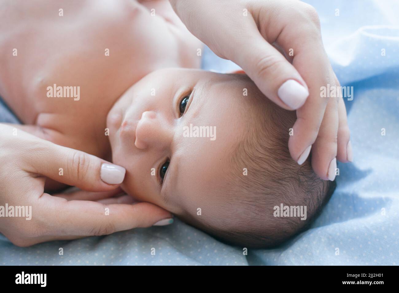 le mani della madre picchiano delicatamente il neonato Foto Stock