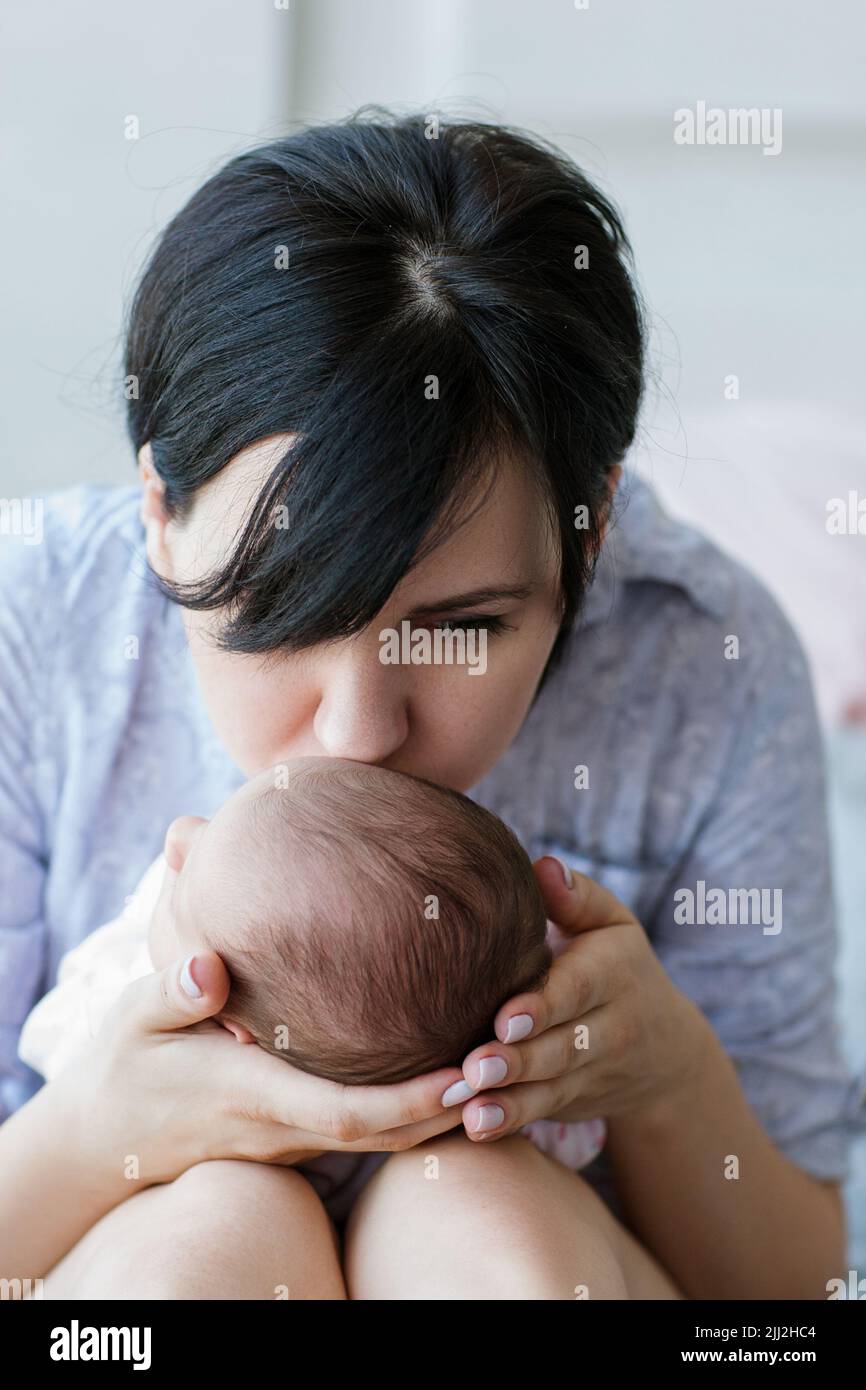 mamma bacia delicatamente il suo neonato Foto Stock