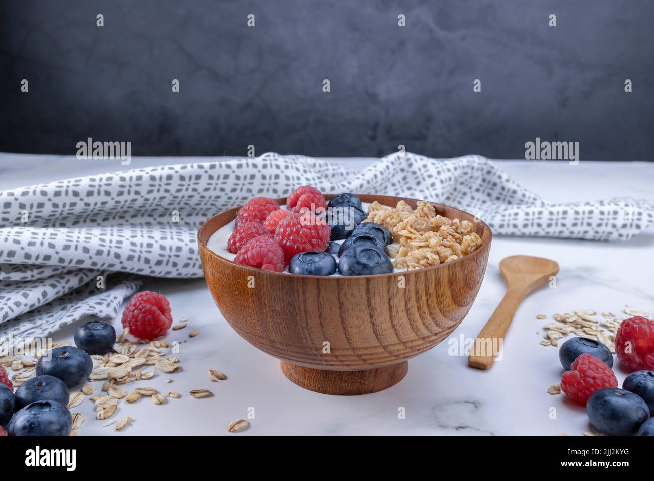 Servire una porzione di yogurt con lampone di mirtillo e fiocchi di avena in un recipiente di legno pronto per essere servito. Alimento sano per concetto di dieta. Frutta muesl Foto Stock