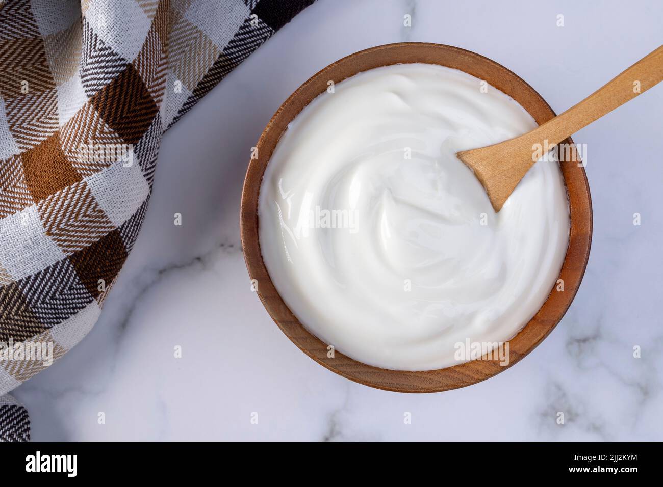 Una porzione di yogurt greco in una ciotola di legno pronta per essere servita. Alimento sano per concetto di dieta. Foto Stock