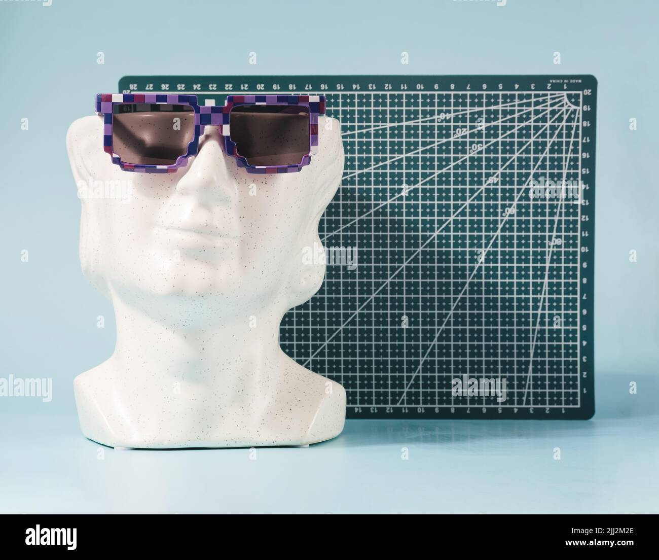 Testa in marmo bianco con occhiali da sole e tavola geometrica sullo sfondo. Concetto futuristico di vacanza. Foto Stock