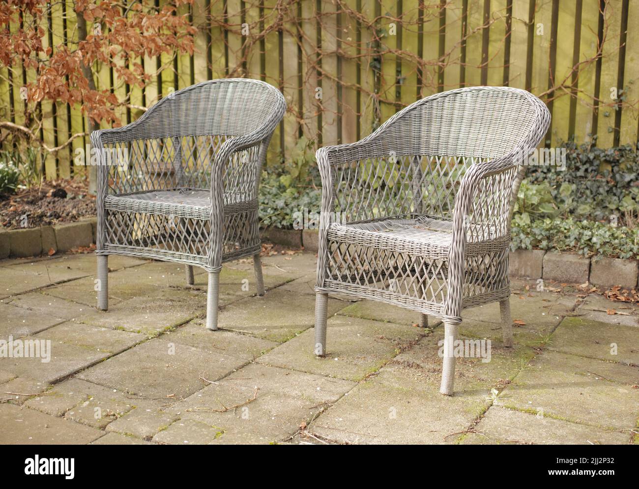Due sedie da patio all'aperto in giardino o cortile. Mobili esterni fatti a mano in un'area salotto o in un cortile. Set di poltrone cottage con tradizionale Foto Stock