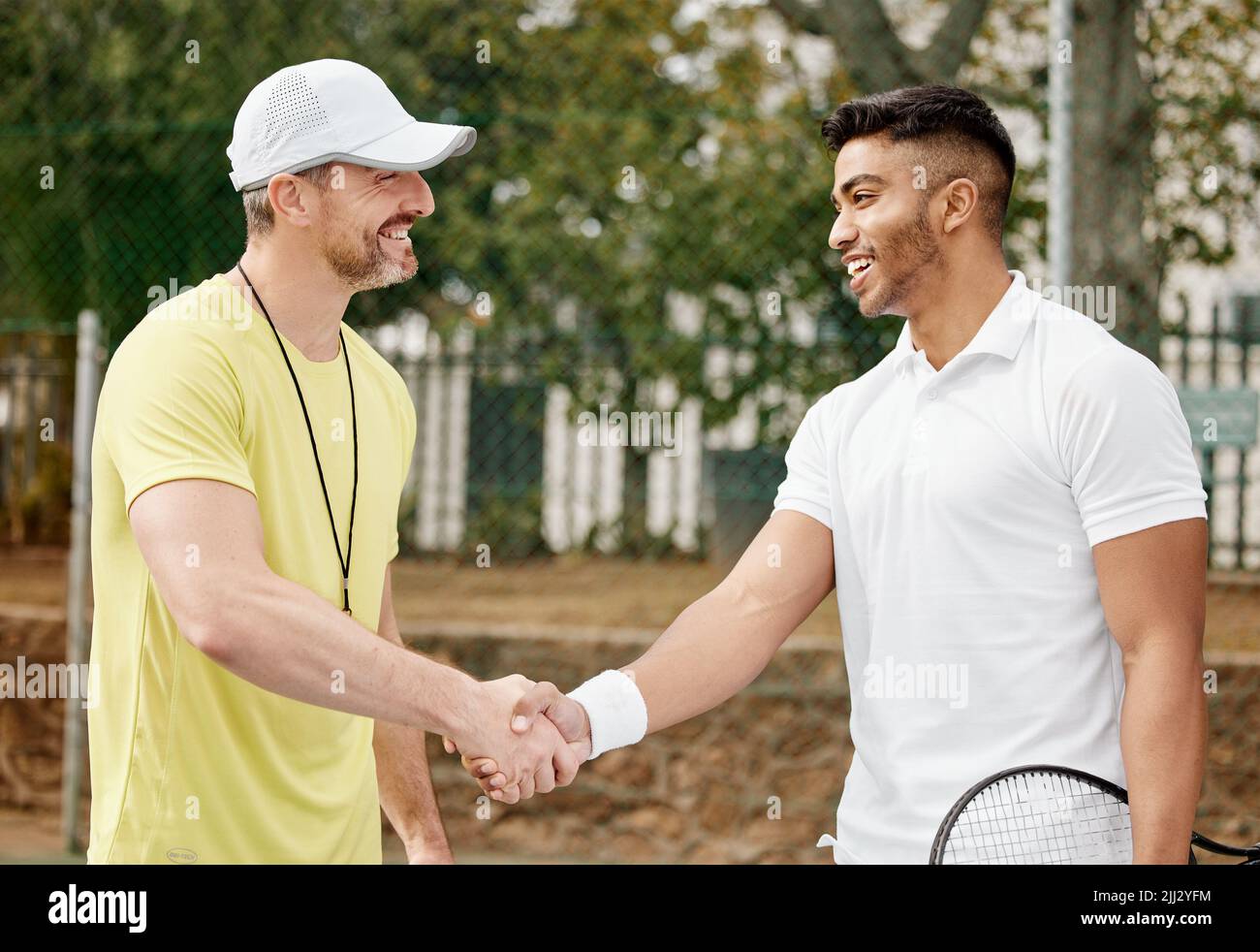Ben suonato. Un bel giovane giocatore di tennis maschile che scuote le mani con il suo allenatore fuori sul campo. Foto Stock