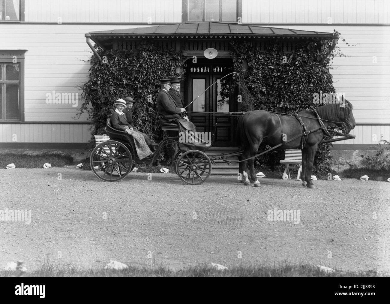 Edificio residenziale, cavallo e carrozza, quattro persone. Foto Stock