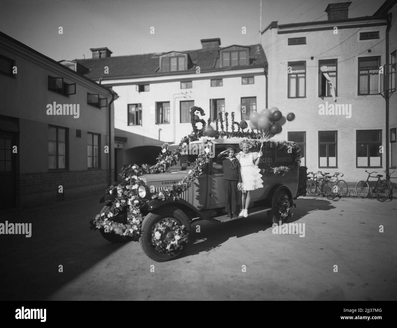 Furgone decorato con fiori, del marchio Bedford Six. Due bambini. Buildings. Gullberg's produttore alimentare Arvid Gullberg Foto Stock