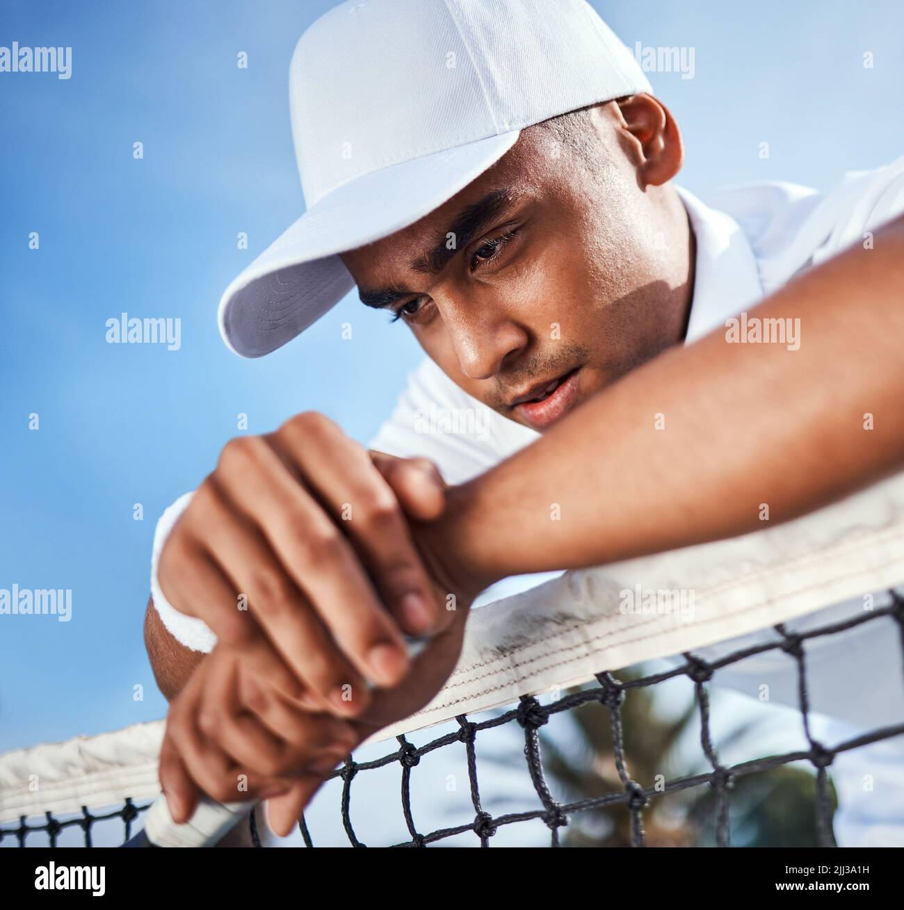 Dai, mettiti insieme. Un bel giovane uomo che si appoggia su una rete da tennis e che si sente deluso dopo la pratica. Foto Stock