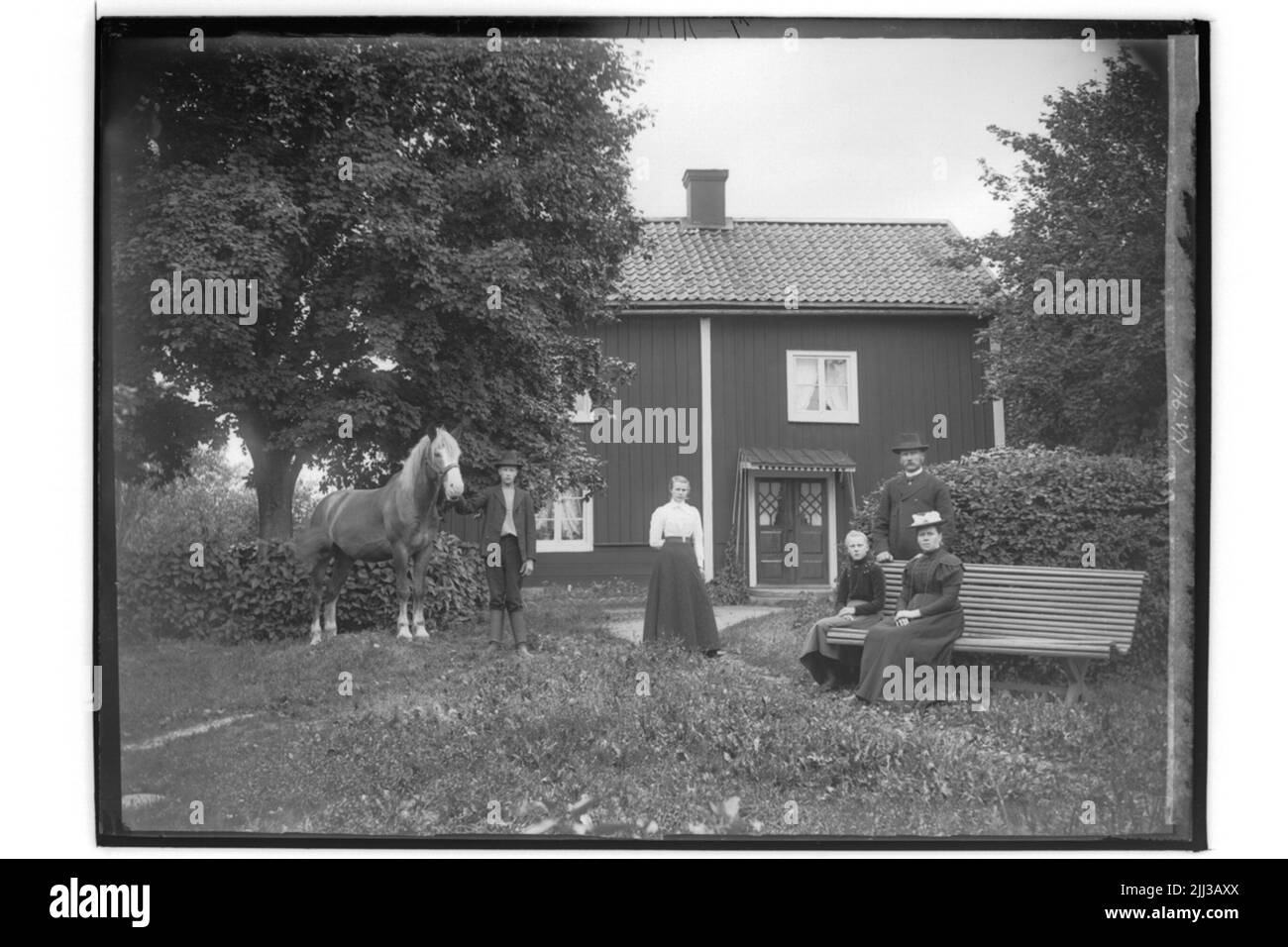 Edificio residenziale a due piani, Närkesstuga. Famiglia gruppo 5 persone e un cavallo di fronte al cottage.c.o. Erikson. Foto Stock