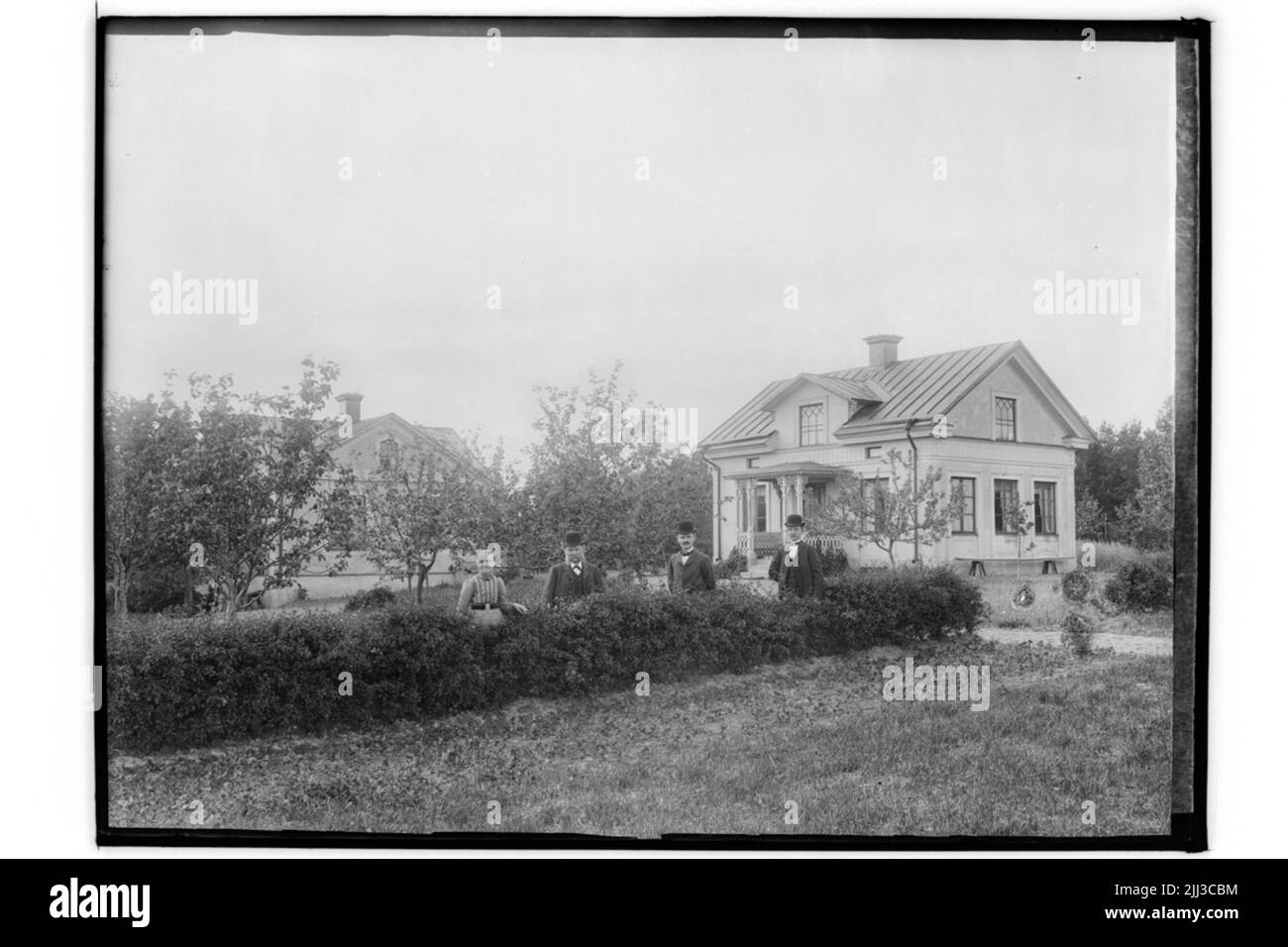 Due edifici residenziali, 4 persone ad una hedge.Gustaf Andersson Foto Stock