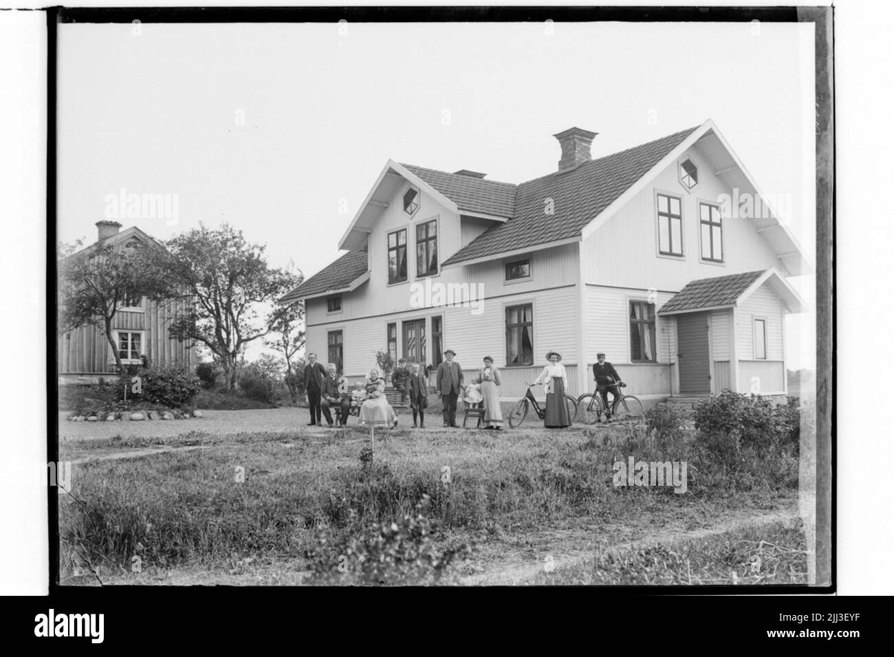Edifici residenziali a un piano e mezzo con fornello frontale e ingresso. Dieci persone di fronte alla casa. Foto Stock
