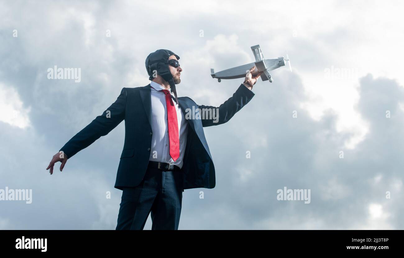 uomo d'affari in abito e cappello pilota lancia giocattolo aereo su sfondo cielo. aspirazioni Foto Stock