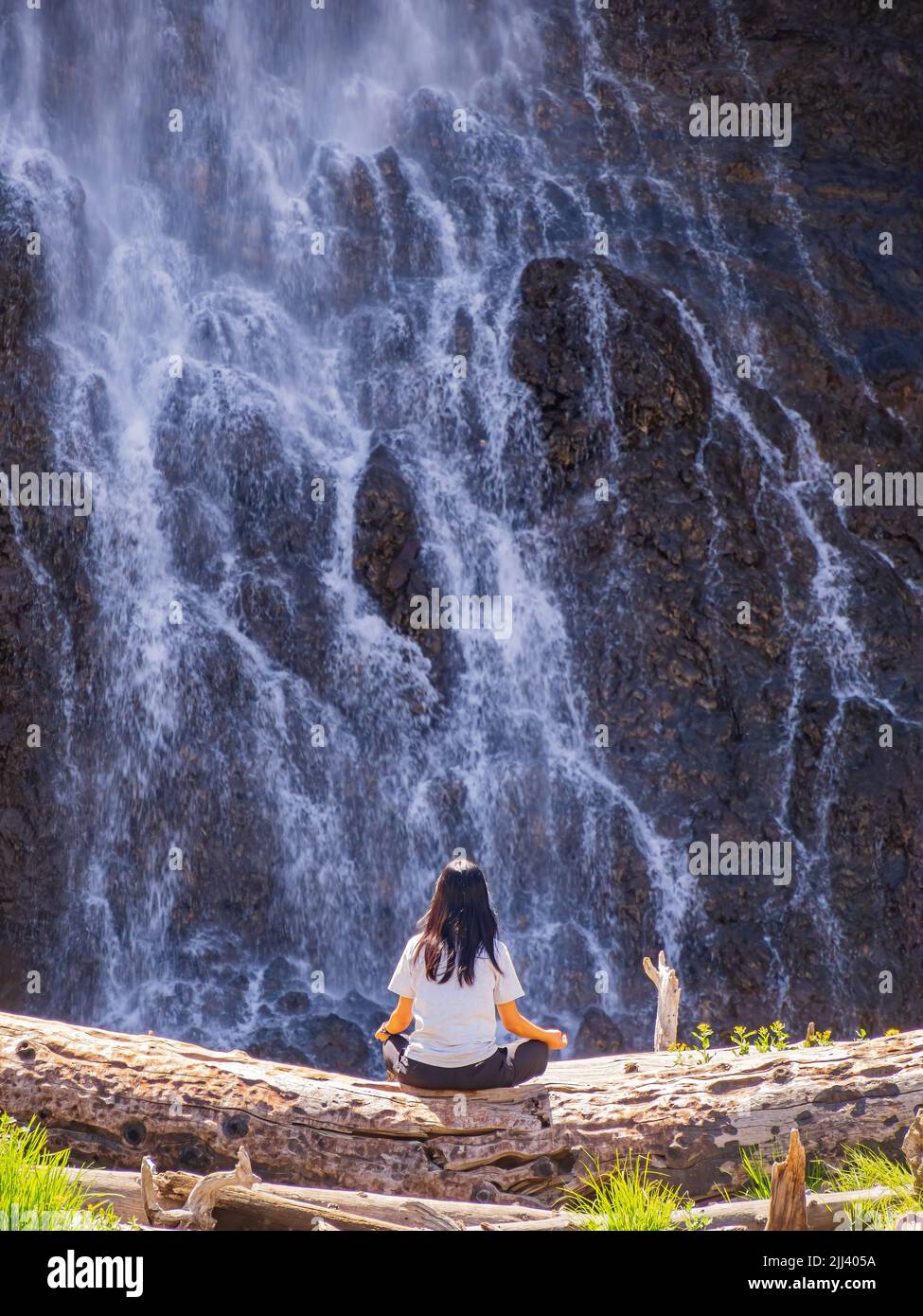 Donna che medita di fronte alle cascate Fairy Falls nel Wyoming Foto Stock