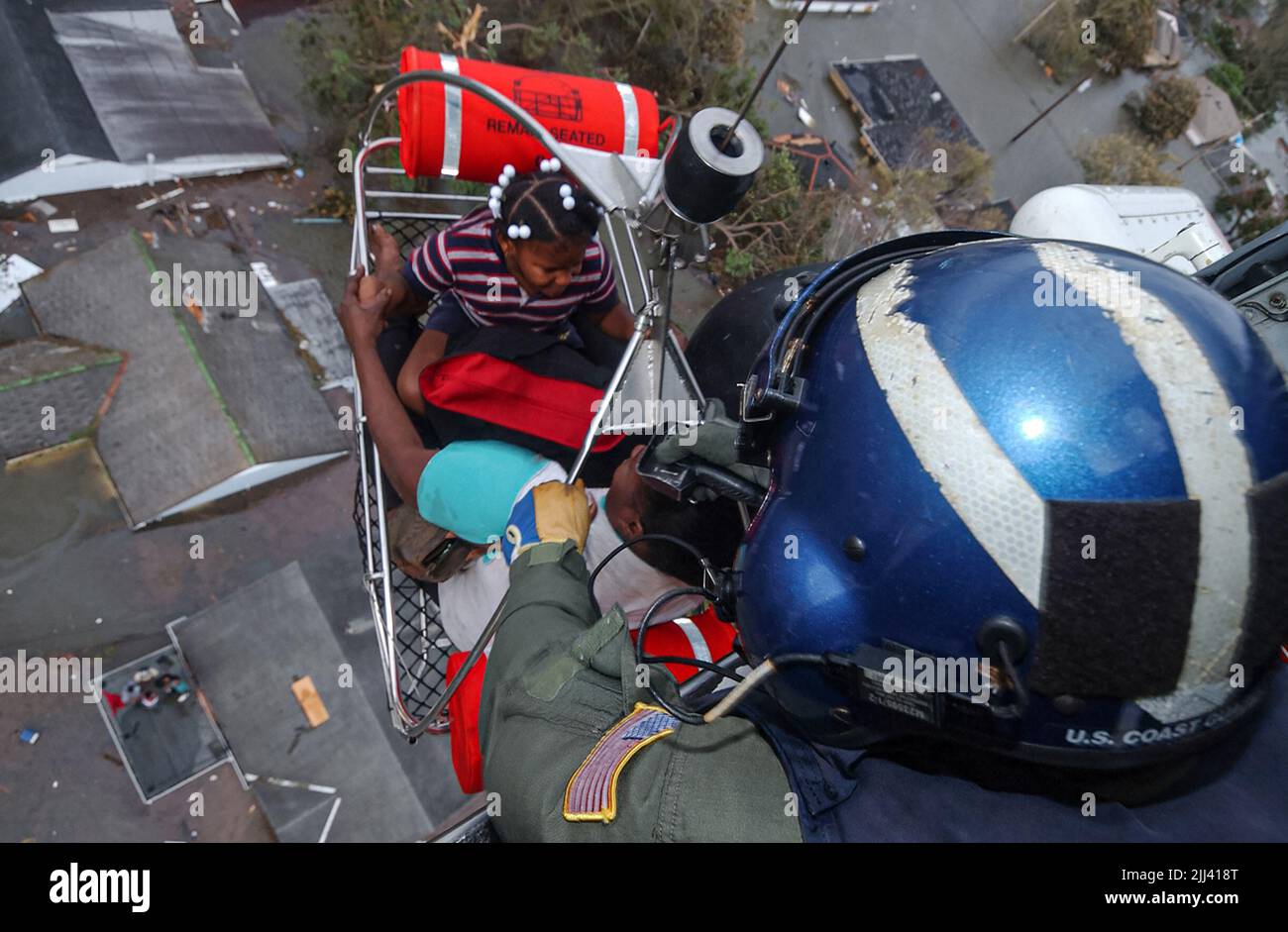 Steven Huerta allena due bambini in un elicottero di salvataggio della Guardia Costiera durante l'uragano Katrina che alluvetta il 29 agosto 2005 a New Orleans, Louisiana. Altri osservano dal basso mentre i bambini sono fra molti cittadini per essere salvati dai loro tetti a causa dell'alluvione. Foto Stock
