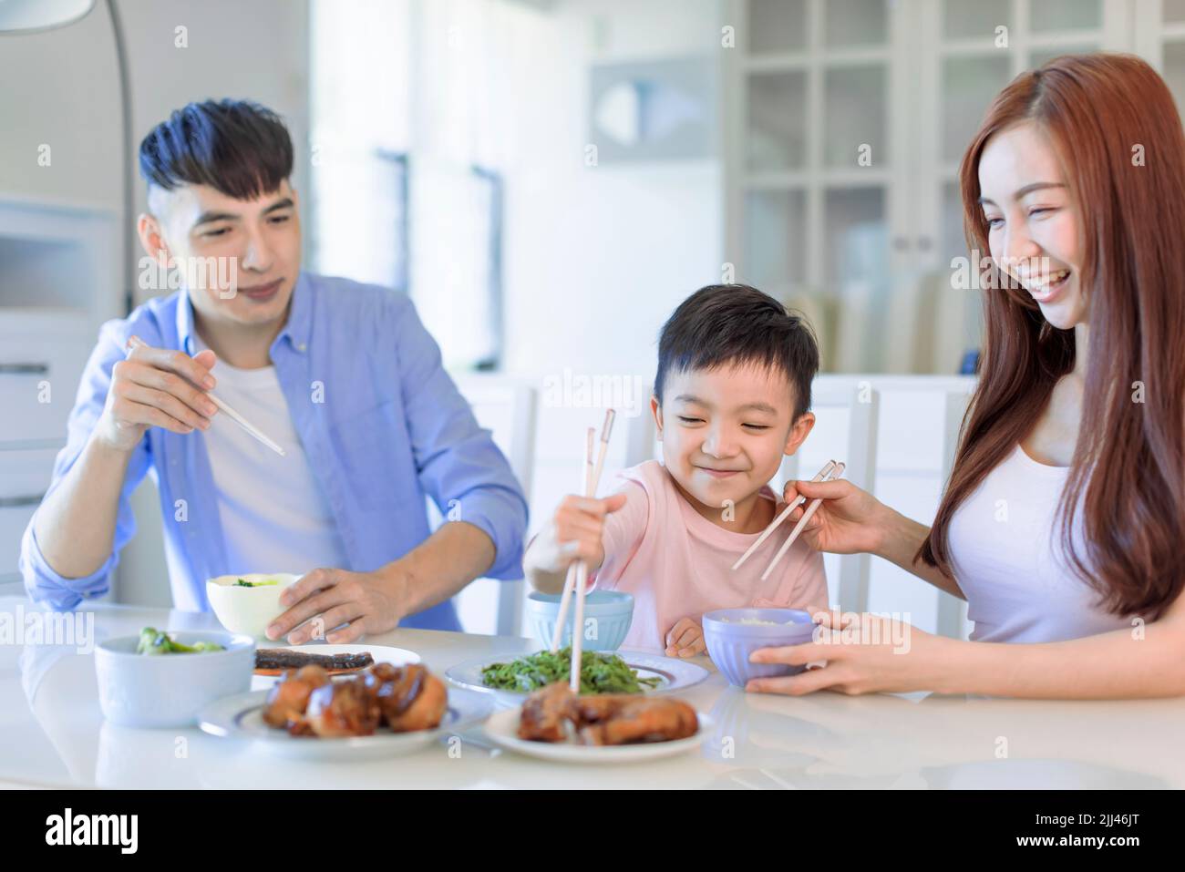 il ragazzo si diverta a mangiare cibo con padre e madre. Una felice famiglia asiatica che cena a casa Foto Stock