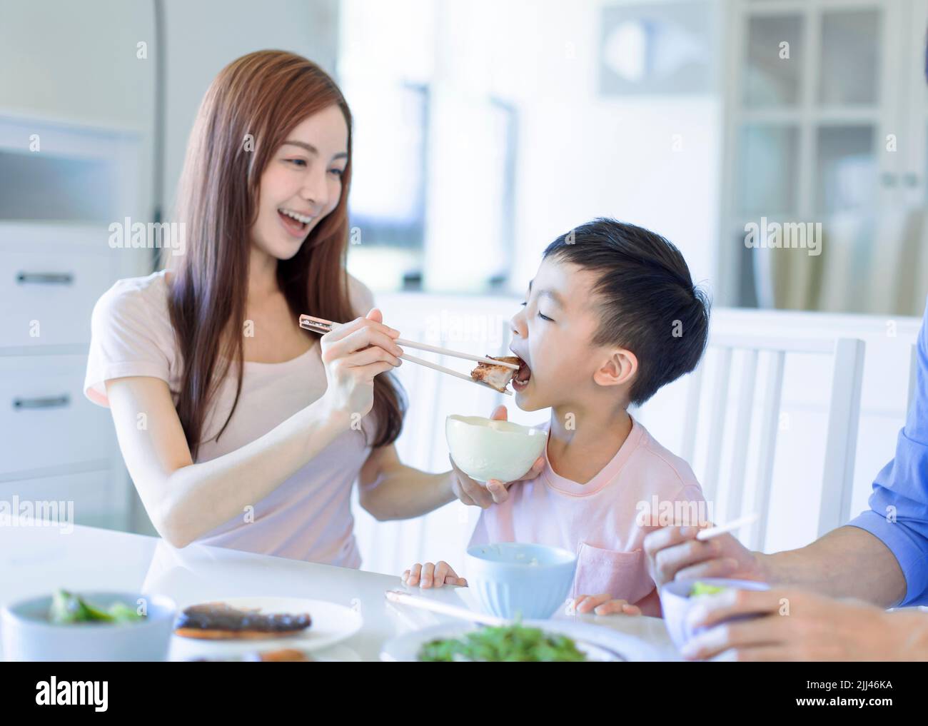 il ragazzo si diverta a mangiare cibo con padre e madre. Una felice famiglia asiatica che cena a casa Foto Stock