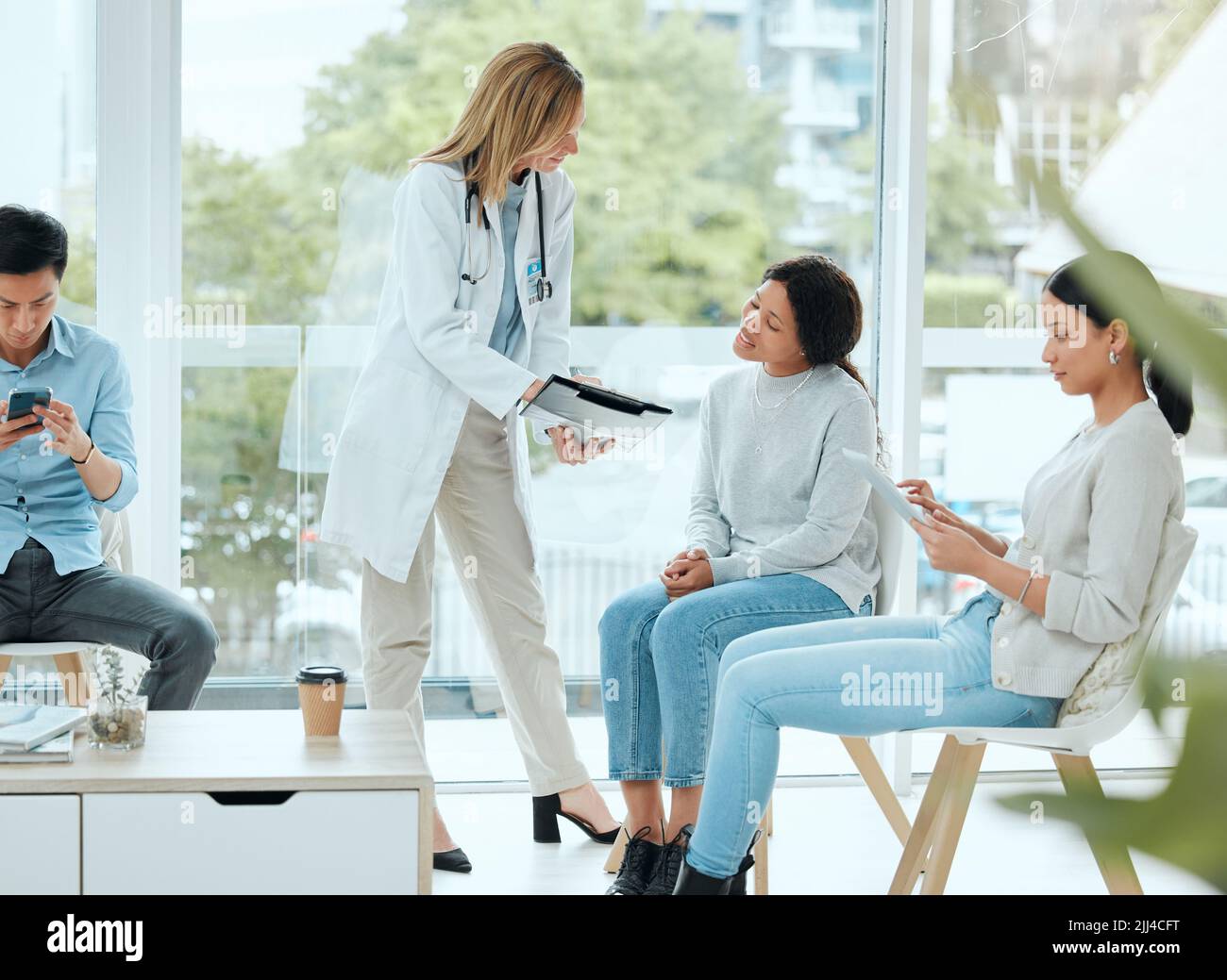 Potreste iniziarli. Un medico maturo ed il suo paziente che discutono i suoi ultimi risultati nella stanza d'attesa. Foto Stock