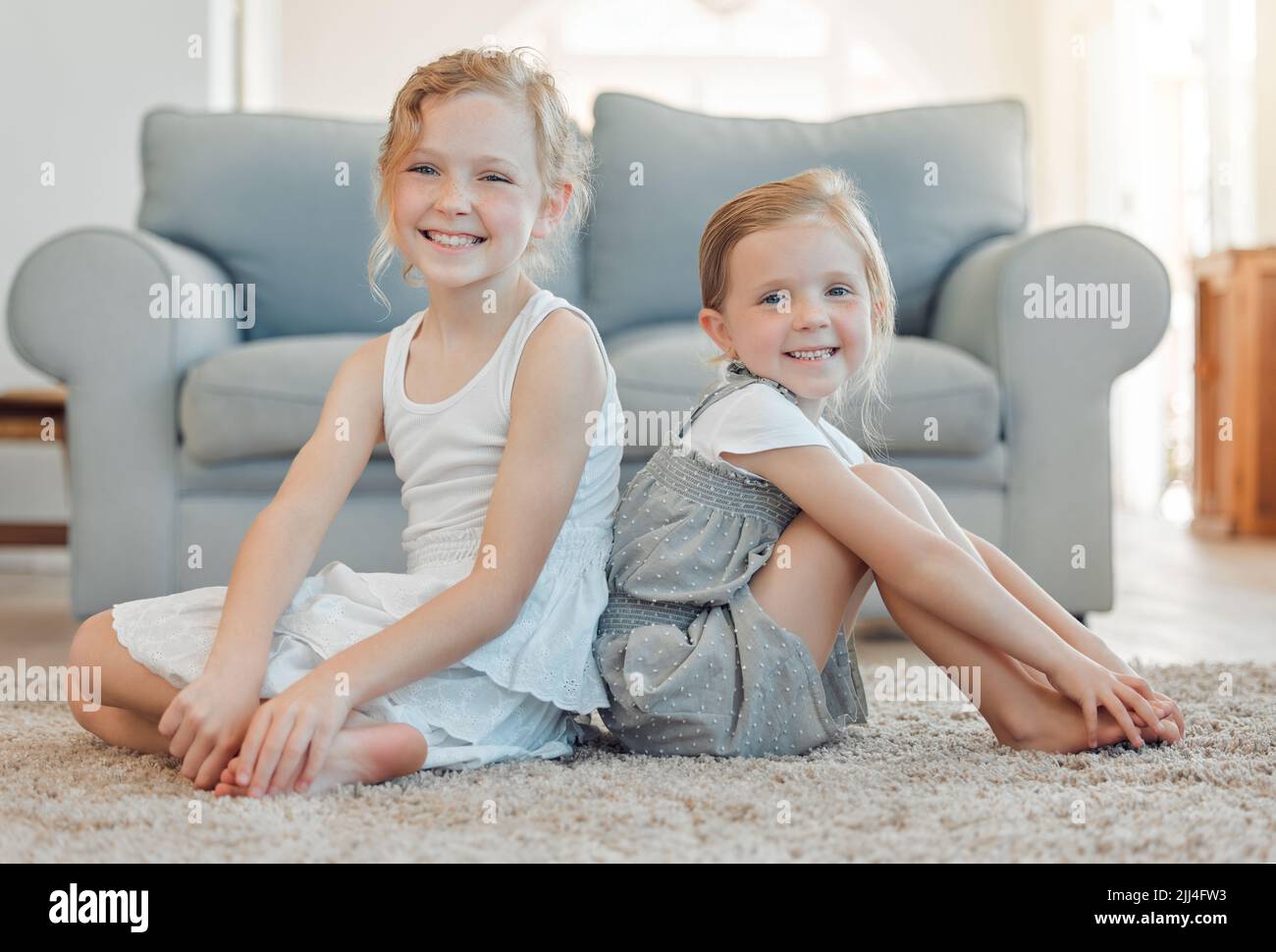 Indovinate chi ha ottenuto la vostra schiena per la vita. Due ragazze piccole che si legano mentre si siedono sul pavimento insieme nel paese. Foto Stock