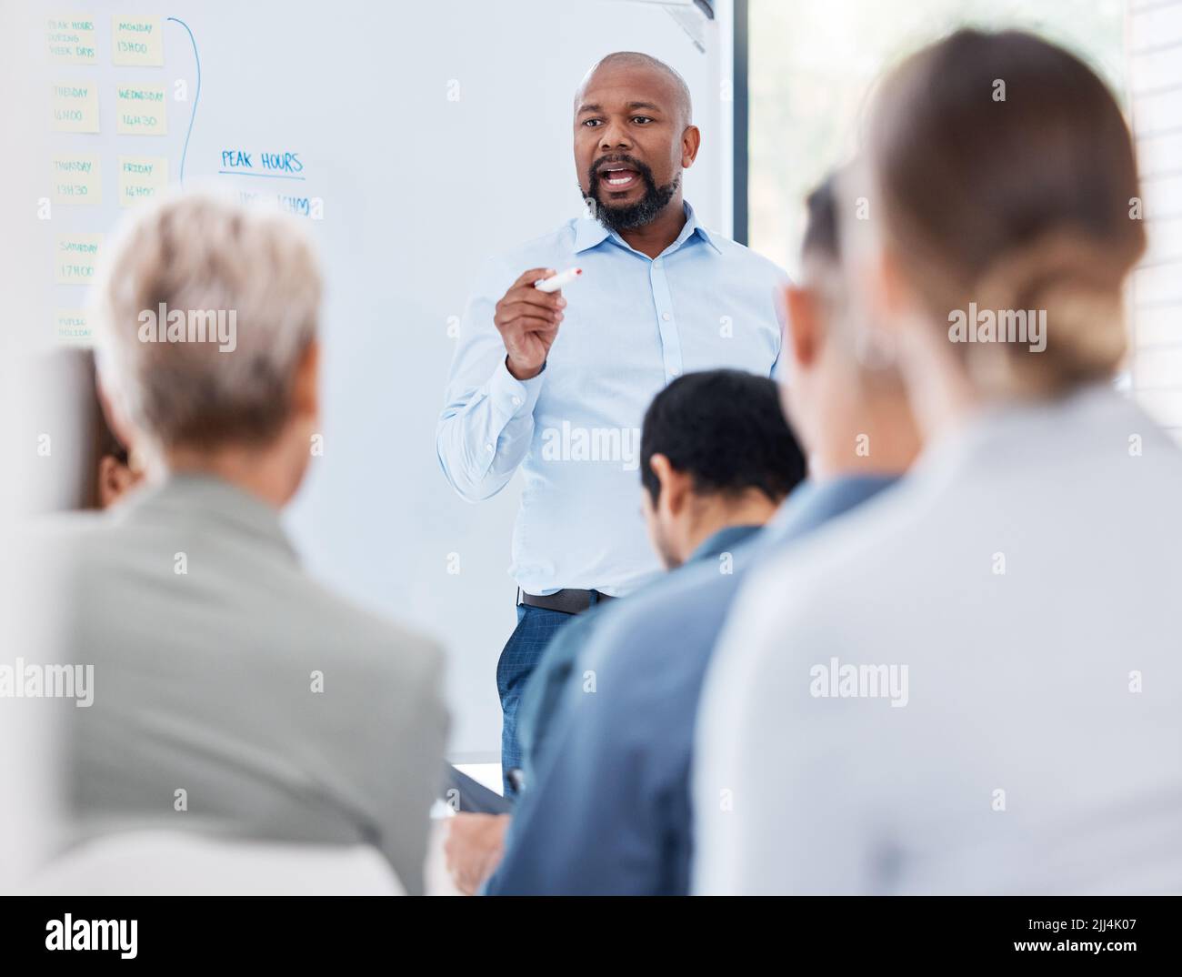 Il team di formazione e di insegnamento dei manager aziendali afroamericani maturi in ufficio. Uomo d'affari nero che usa una lavagna per parlare e spiegare Foto Stock