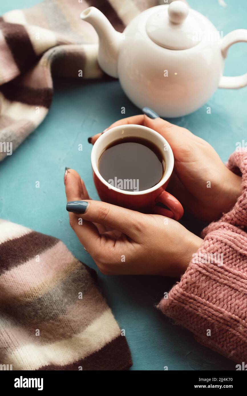 La donna tiene una tazza di tè caldo sullo sfondo blu Foto Stock