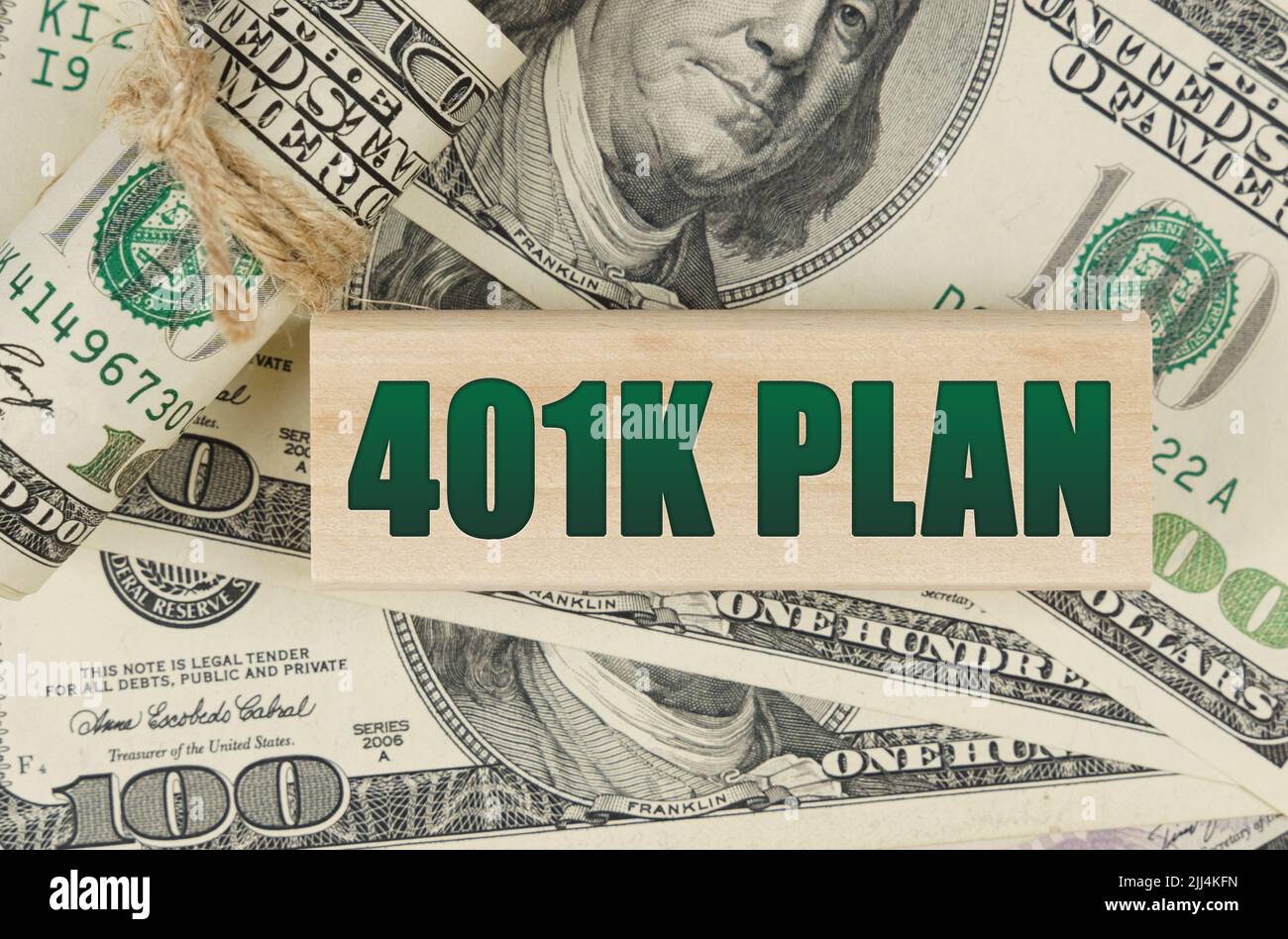 Concetto di business e finanza. Sui dollari c'è una targa di legno con l'iscrizione - PIANO 401K Foto Stock