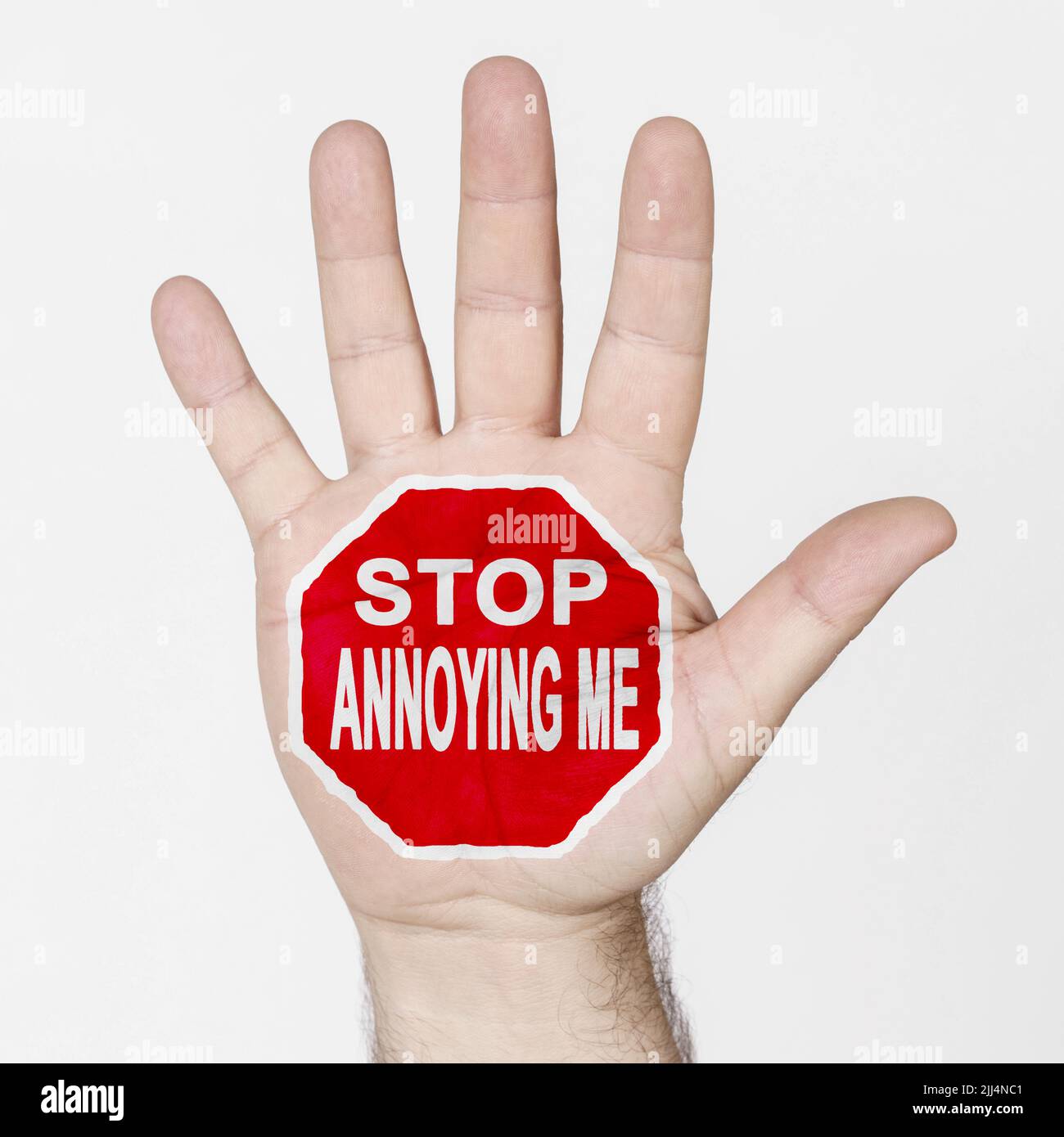 Sul palmo della mano c'è un segno di stop con l'iscrizione - SMETTA DI INFASTIDIRMI. Isolato su sfondo bianco. Foto Stock