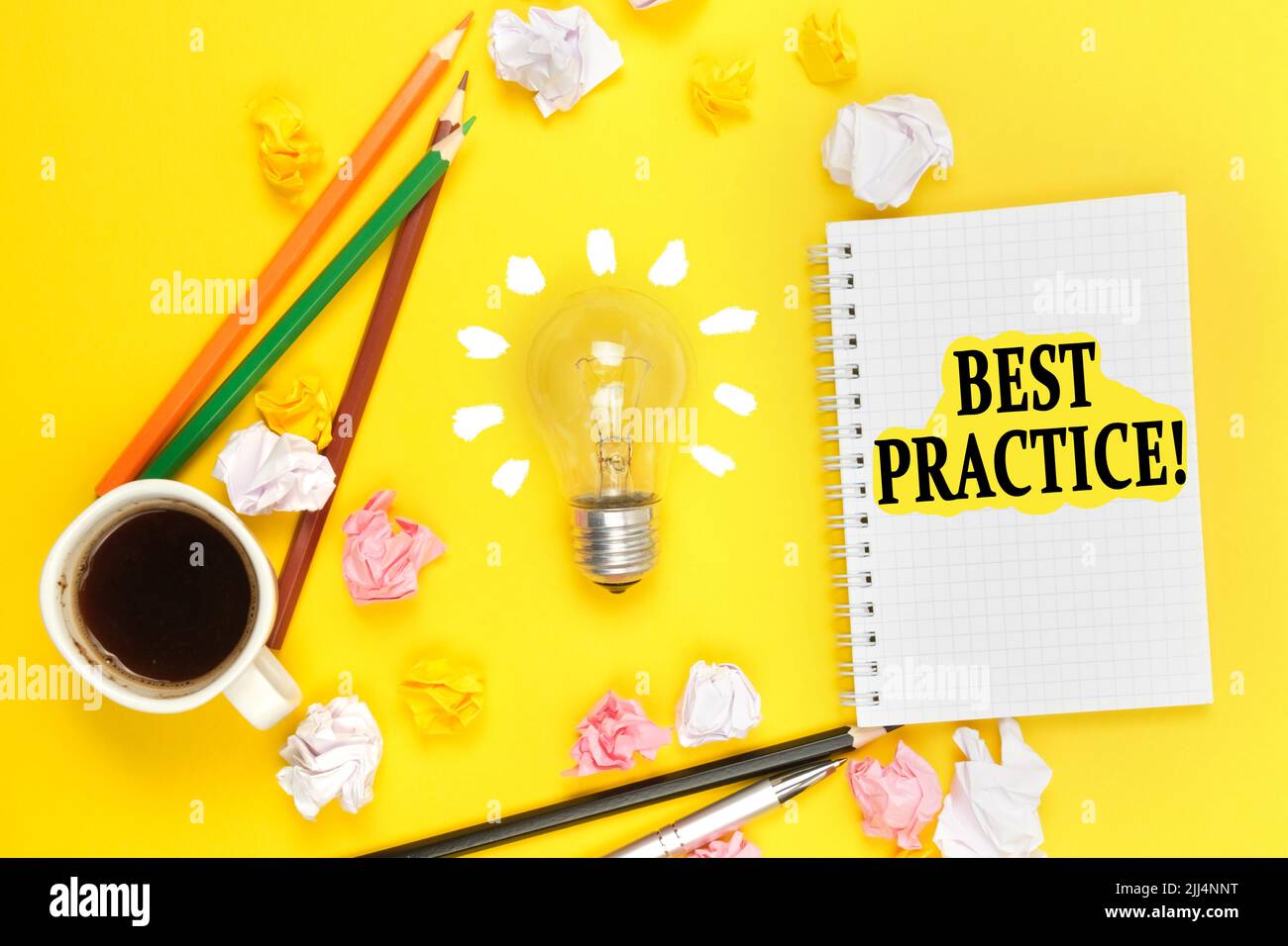 Concetto di business e istruzione. Su sfondo giallo, una tazza di caffè, una lampadina, matite, un taccuino con l'iscrizione - BEST PRACTICE Foto Stock