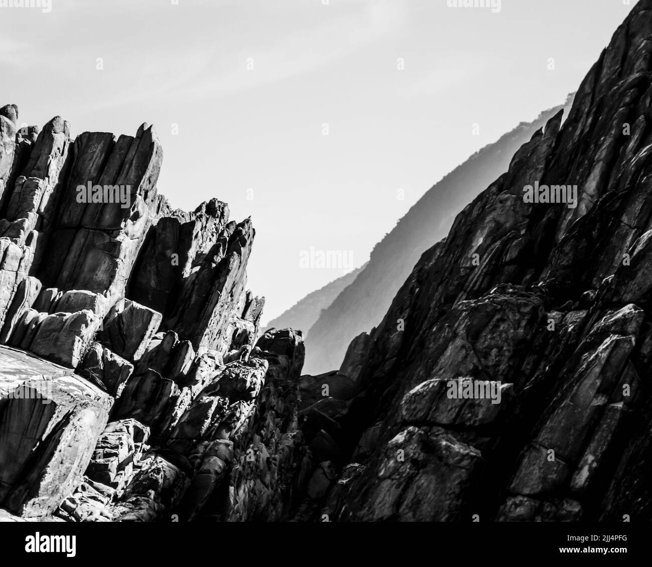 Strati di roccia inclinati, della Costa Tsitsikamma, Sudafrica, con le lontane scogliere blu sullo sfondo. Foto Stock