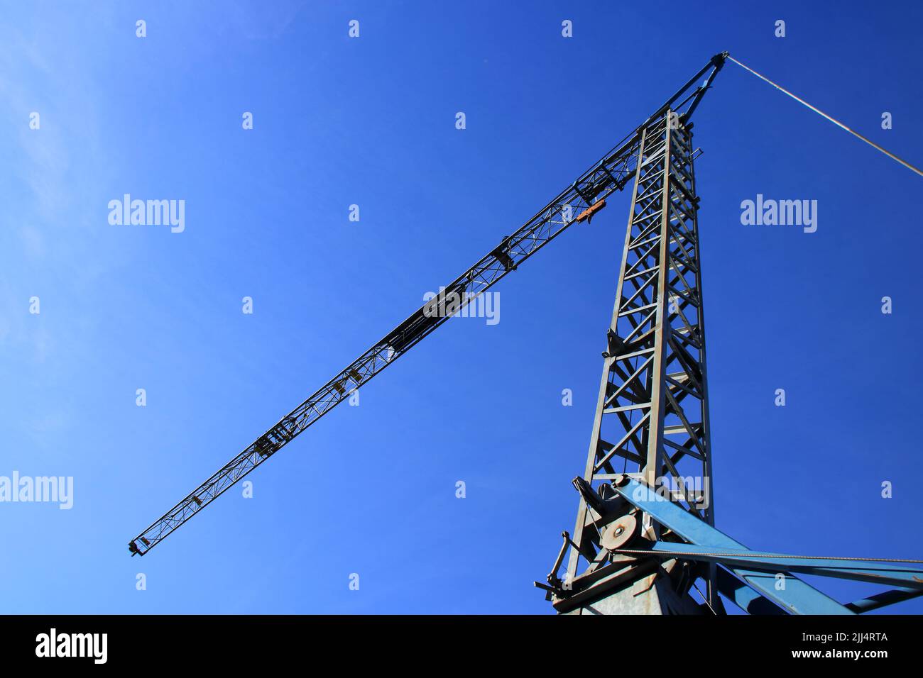 Braccio di una gru da costruzione fotografata da terra contro un cielo blu Foto Stock