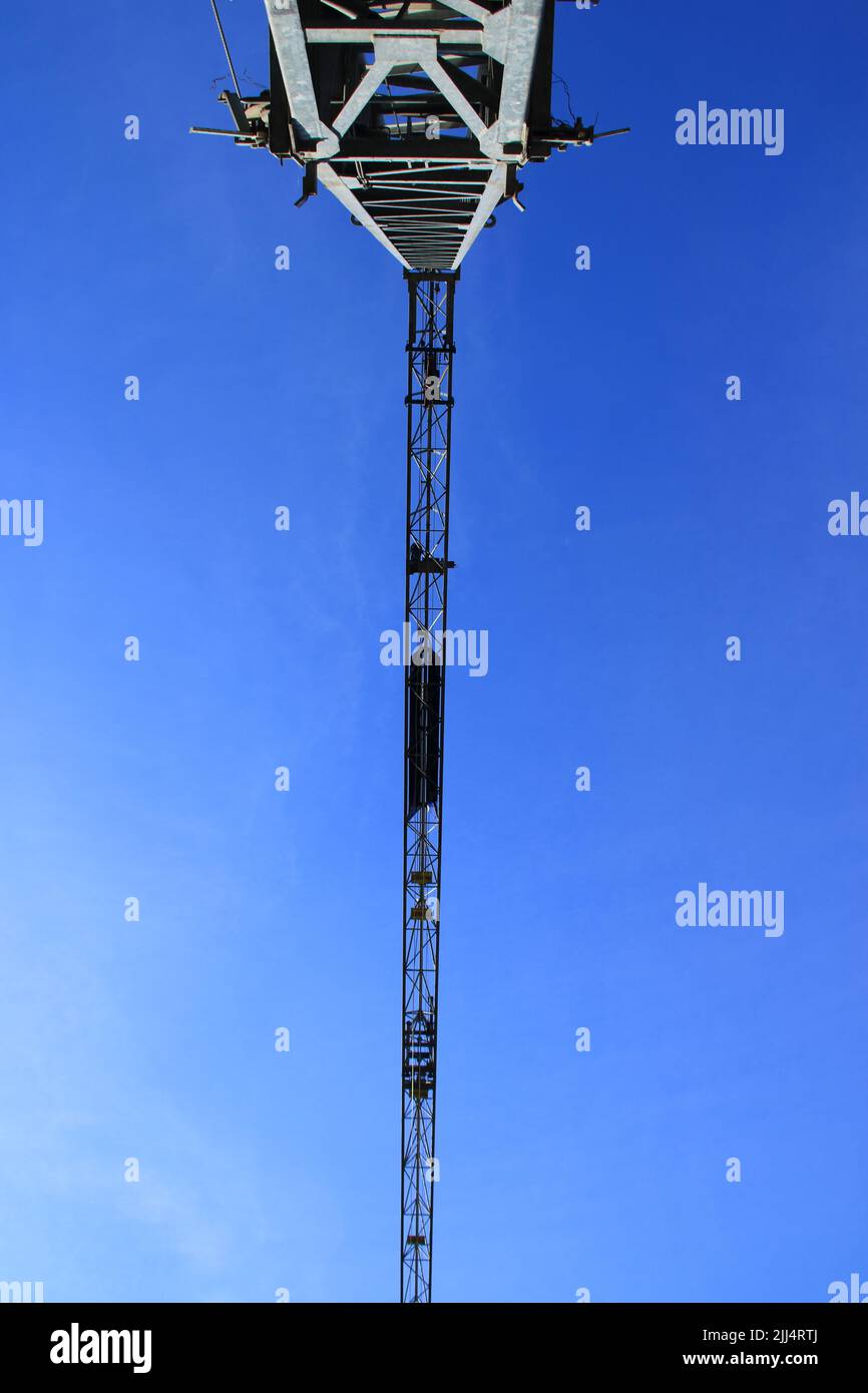 Braccio di una gru da costruzione fotografata da terra contro un cielo blu Foto Stock