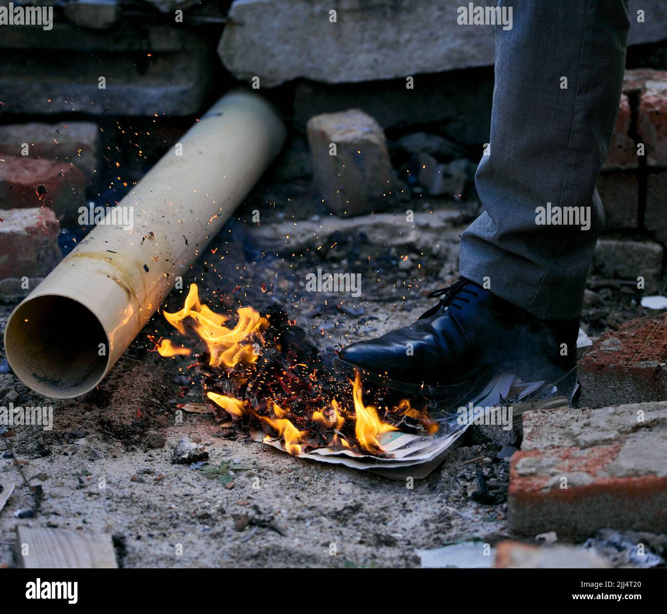 Giocare con il fuoco è un male per chi si brucia: Un uomo irriconoscibile che salpava su una carta bruciata all'interno di una casa bruciata. Foto Stock