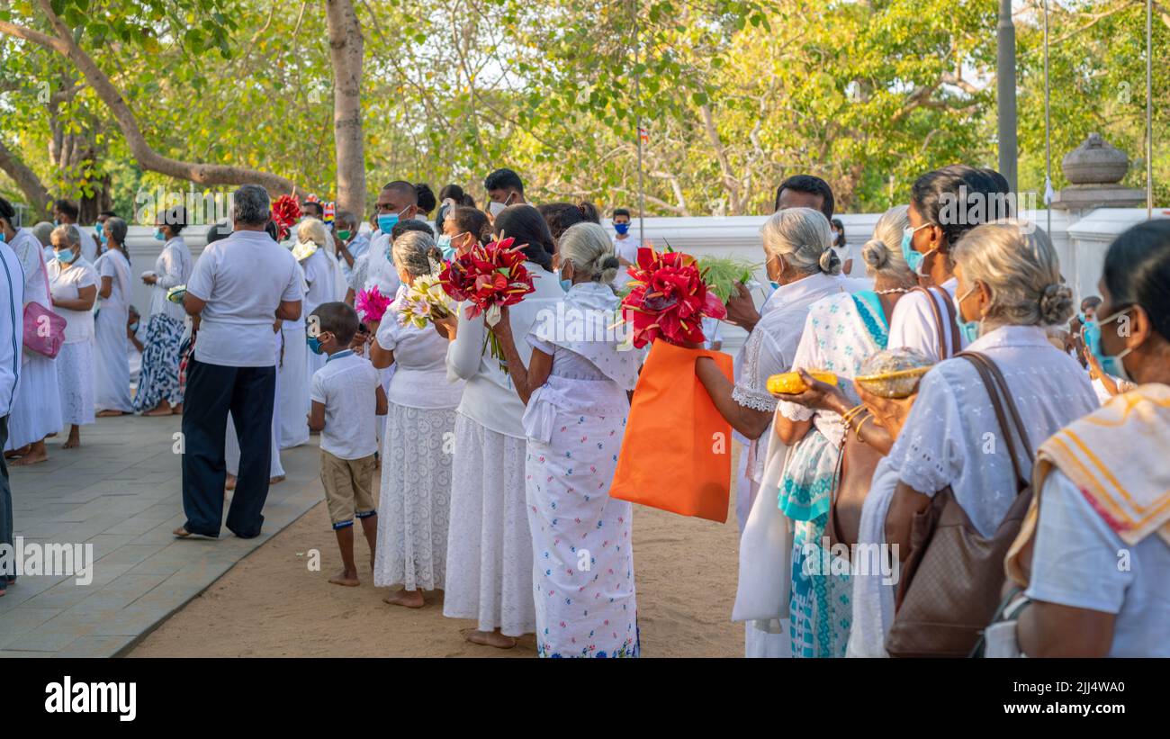 Anuradhapura, Sri Lanka - 03 31 2021: Devoti buddisti che tengono fiori e altre offerte, in fila aspettando la loro possibilità a Jaya Sri Mah Foto Stock