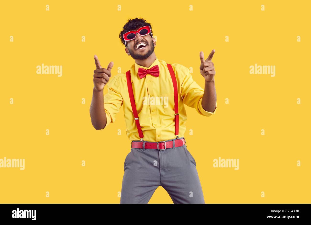 Divertente e alla moda ragazzo indiano bearded divertirsi e ballare isolato su sfondo arancione. Foto Stock