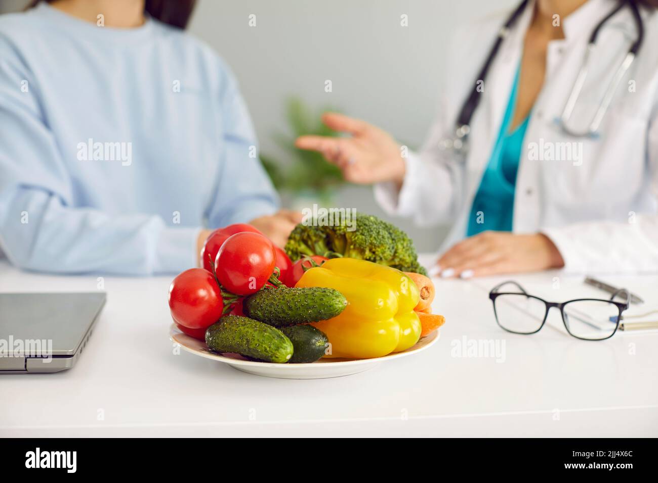 Verdure fresche in cetrioli da piatto, pomodori e peperoni sul tavolo del medico nutrizionista Foto Stock