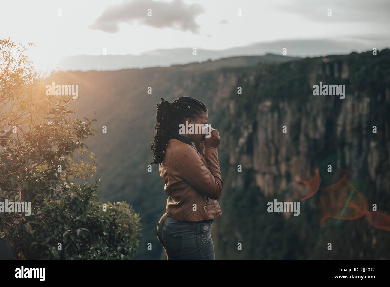 giovane donna turistica utilizzando una fotocamera retrò d'epoca. Giovane donna alla moda che scatta foto nella natura al tramonto Foto Stock