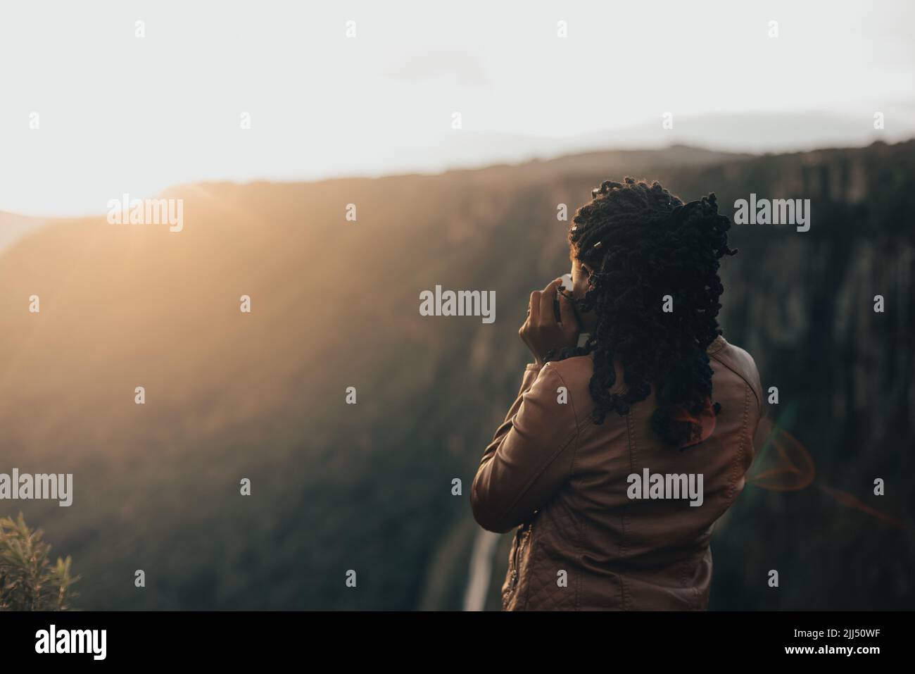 giovane donna turistica utilizzando una fotocamera retrò d'epoca. Giovane donna alla moda che scatta foto nella natura al tramonto Foto Stock