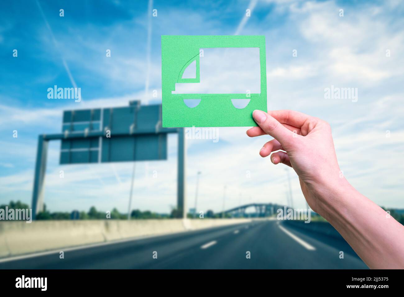 La mano tiene il simbolo verde della logistica contro l'autostrada Foto Stock