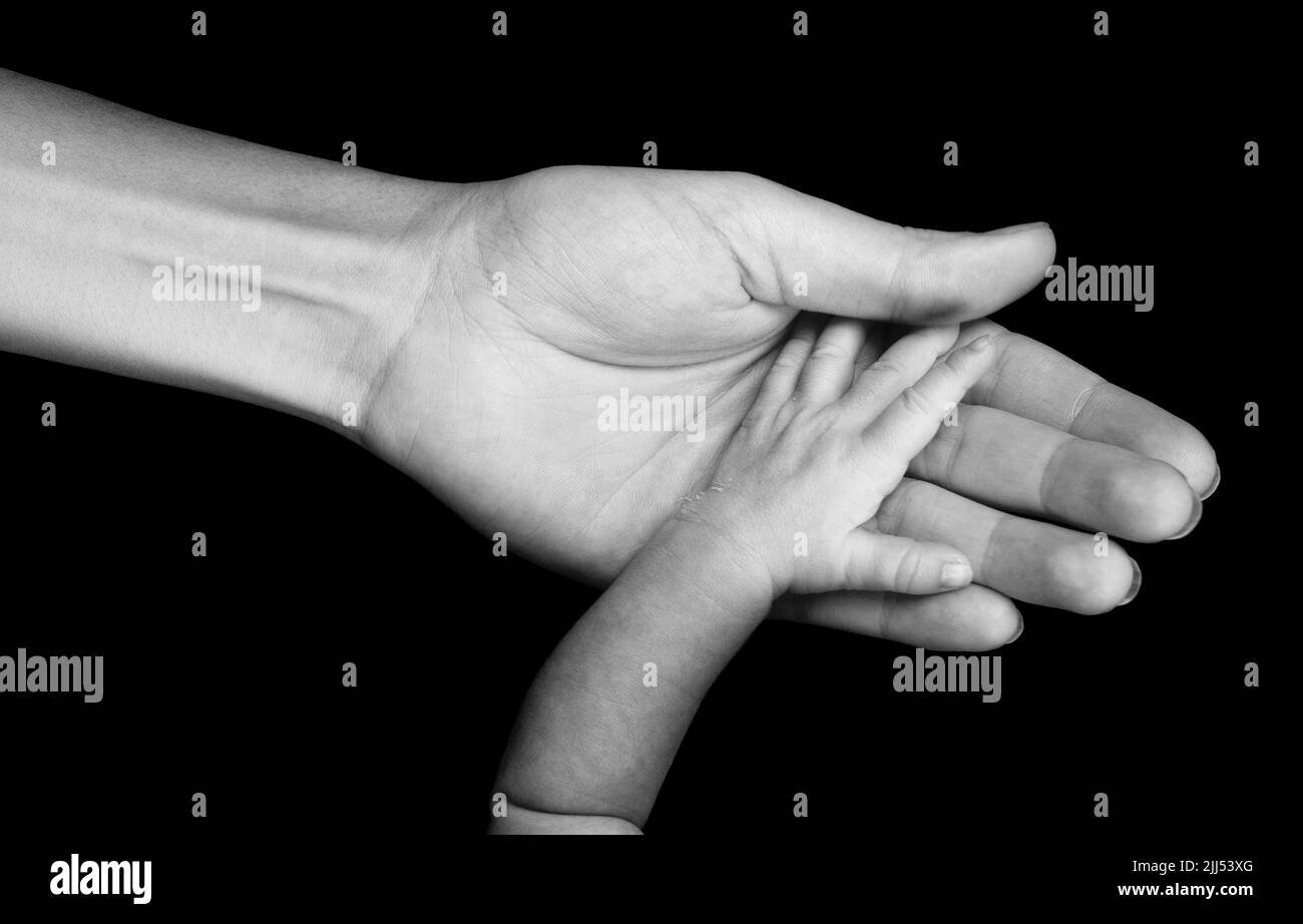 La mano di un neonato è posta sul palmo della mano della madre. Foto Stock