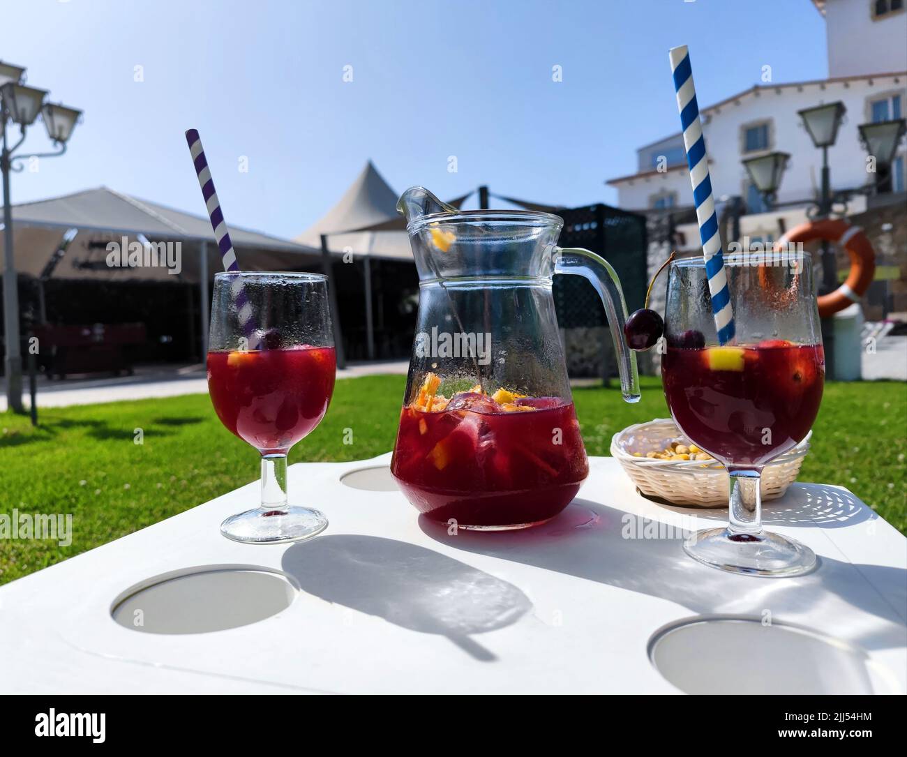 Caraffa con due bicchieri accanto ripieni di deliziosa sangria rossa estiva, frutta fresca e due paillette colorate Foto Stock