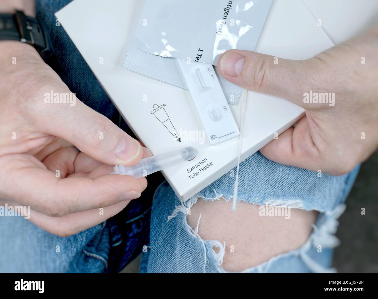 L'uomo, con i jeans strappati, tiene in mano il test rapido Covid-19. Foto Stock