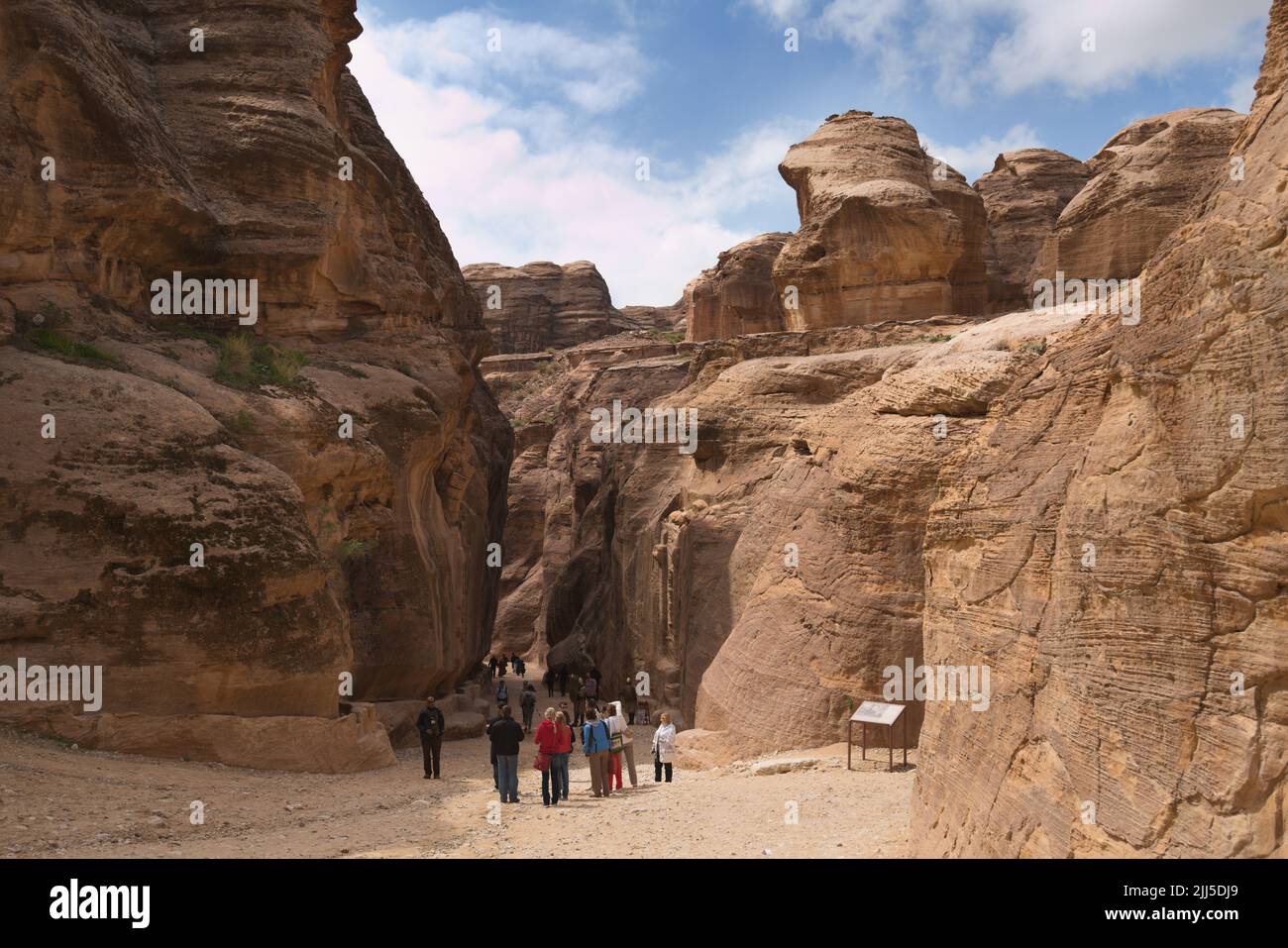 I turisti camminano nel Siq, il canyon dell'antica Petra. Dal 1985, Petra è patrimonio dell'umanità dell'UNESCO Foto Stock