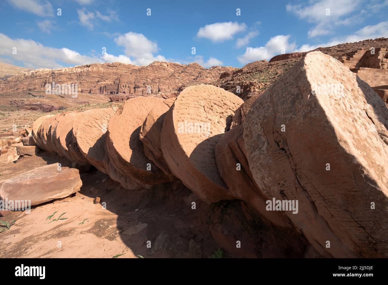 Colonne in rovina in strada colonnata contro le tombe nabatee nell'antica città di Petra, Giordania, patrimonio dell'umanità dell'UNESCO dal 1985 Foto Stock