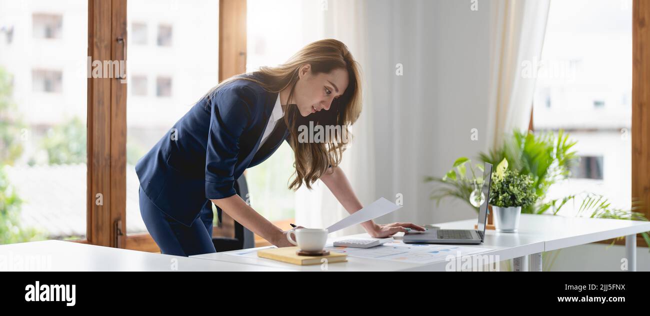 Ritratto fiducioso donna d'affari asiatica che lavora al laptop per rapporto grafico finanziario in ufficio. Foto Stock