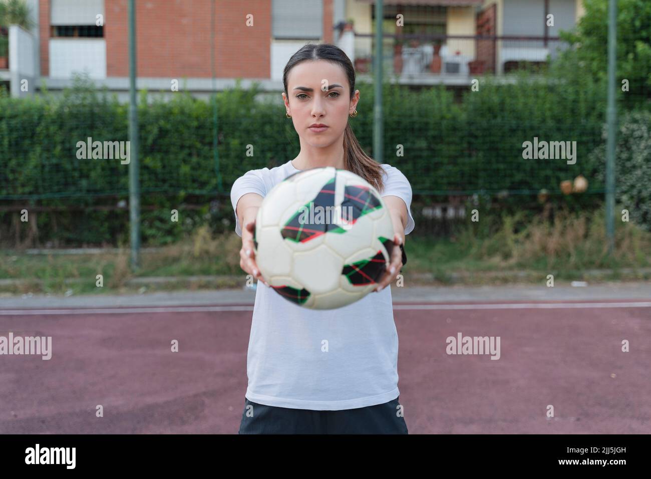 Giovane donna fiduciosa che mostra palla in piedi in campo di calcio Foto Stock