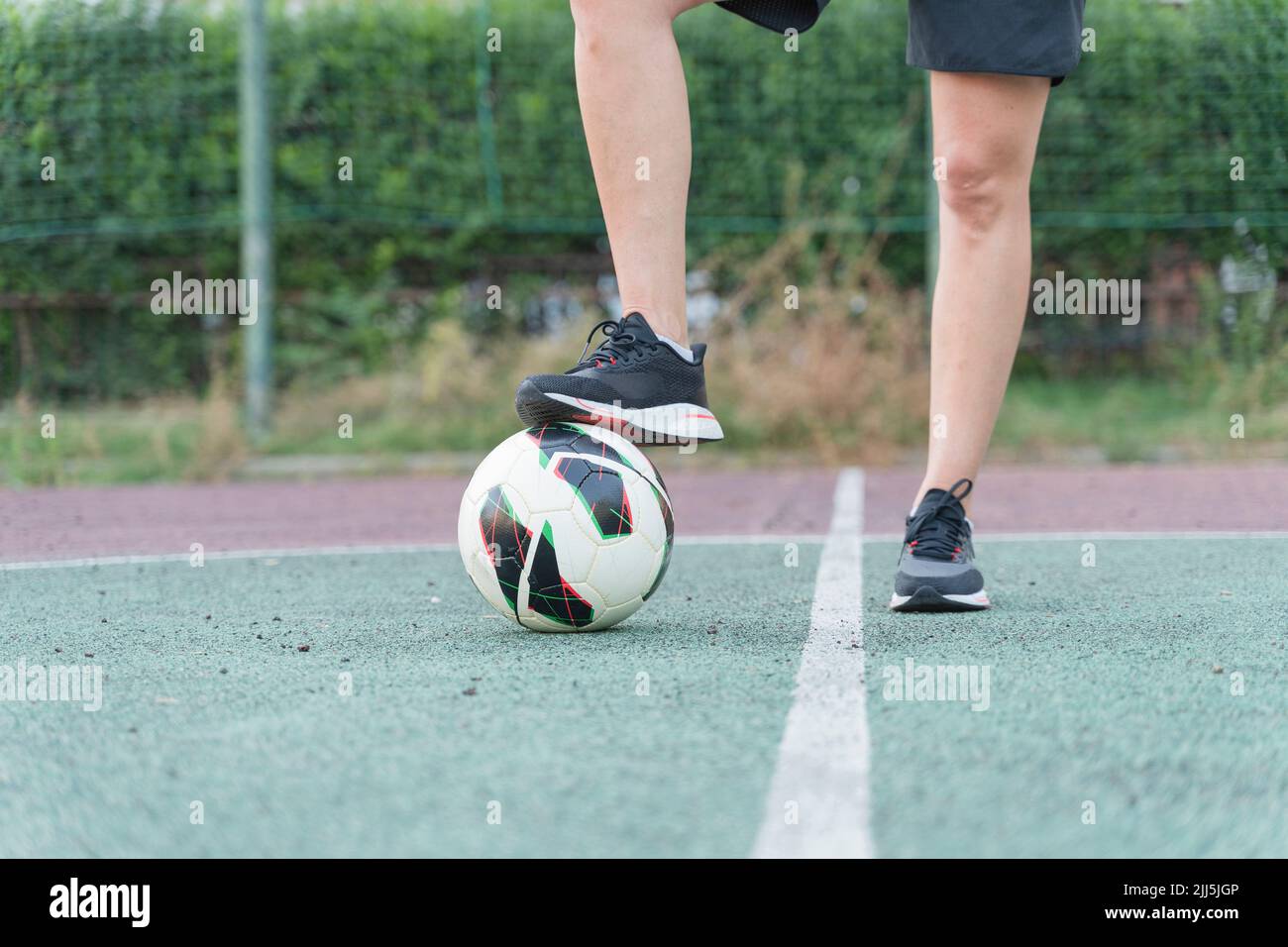 Donna con gamba sul pallone da calcio in campo sportivo Foto Stock