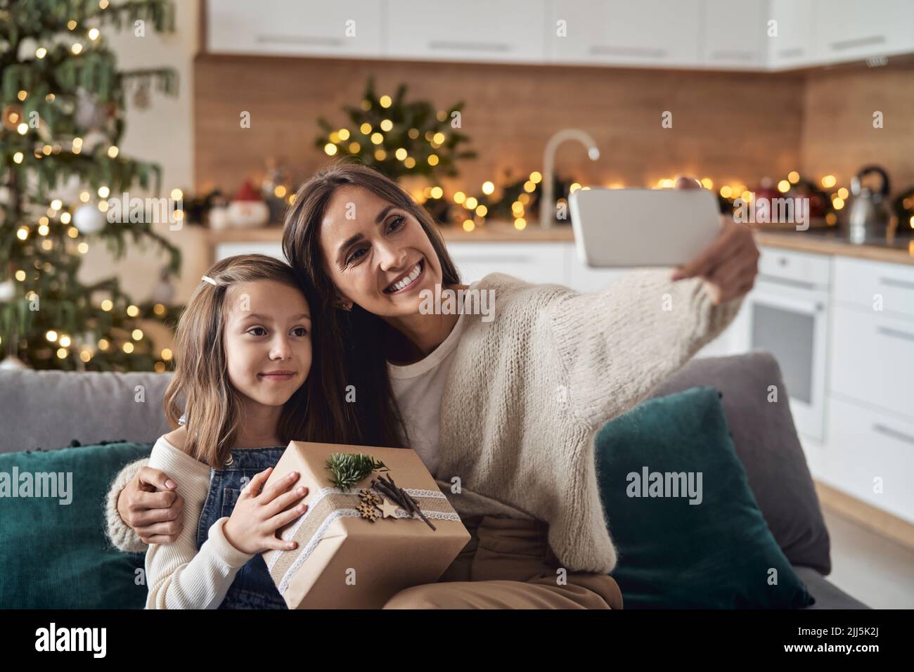 Donna felice che prende selfie con la figlia attraverso lo smartphone a casa Foto Stock